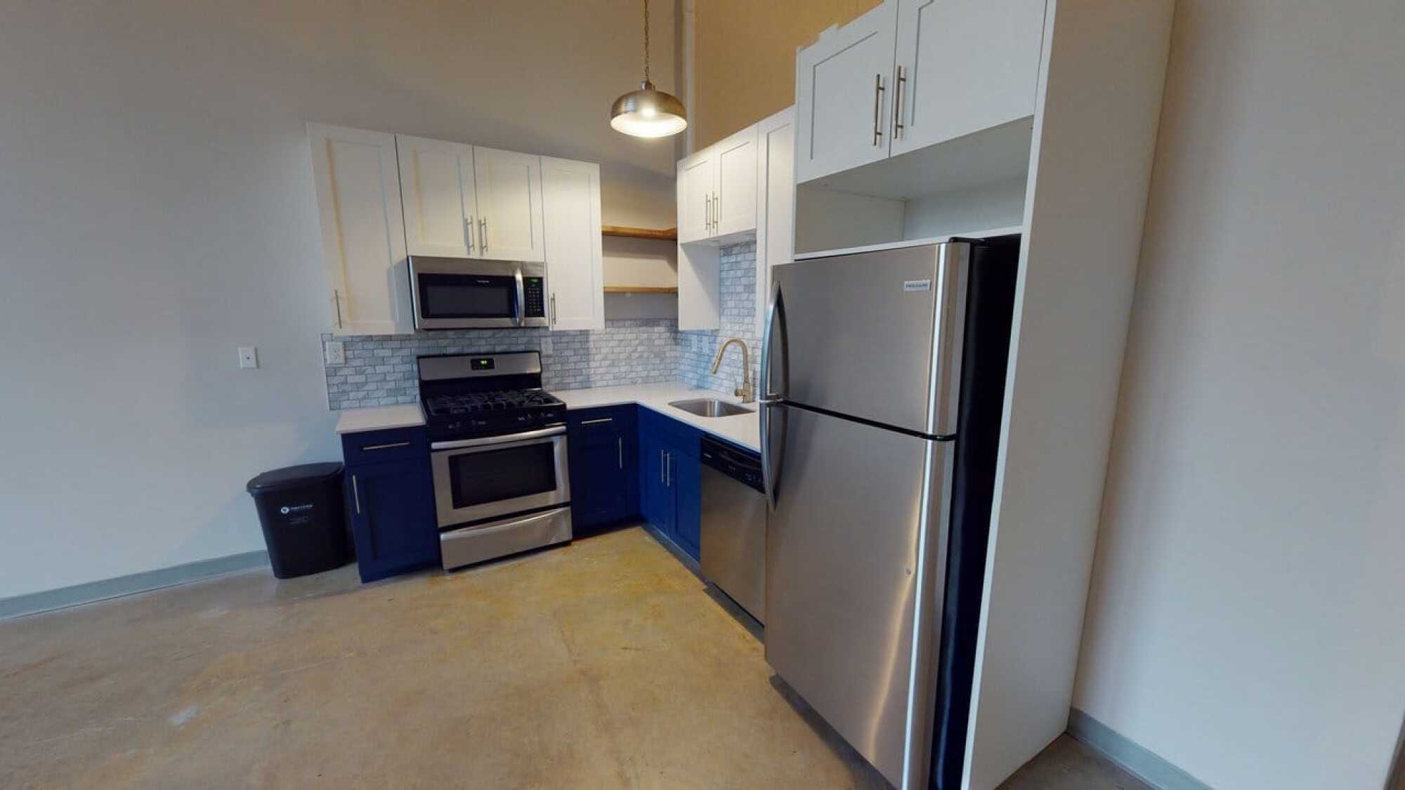 Modern kitchen with stainless steel appliances, white cabinets, blue lower cabinets, and a subway tile backsplash.