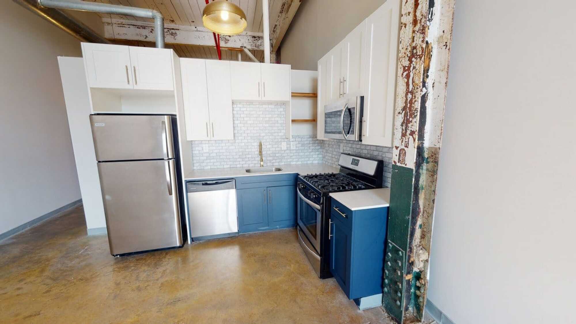 Small modern kitchen with stainless steel appliances, white upper cabinets, blue lower cabinets, and a subway tile backsplash.