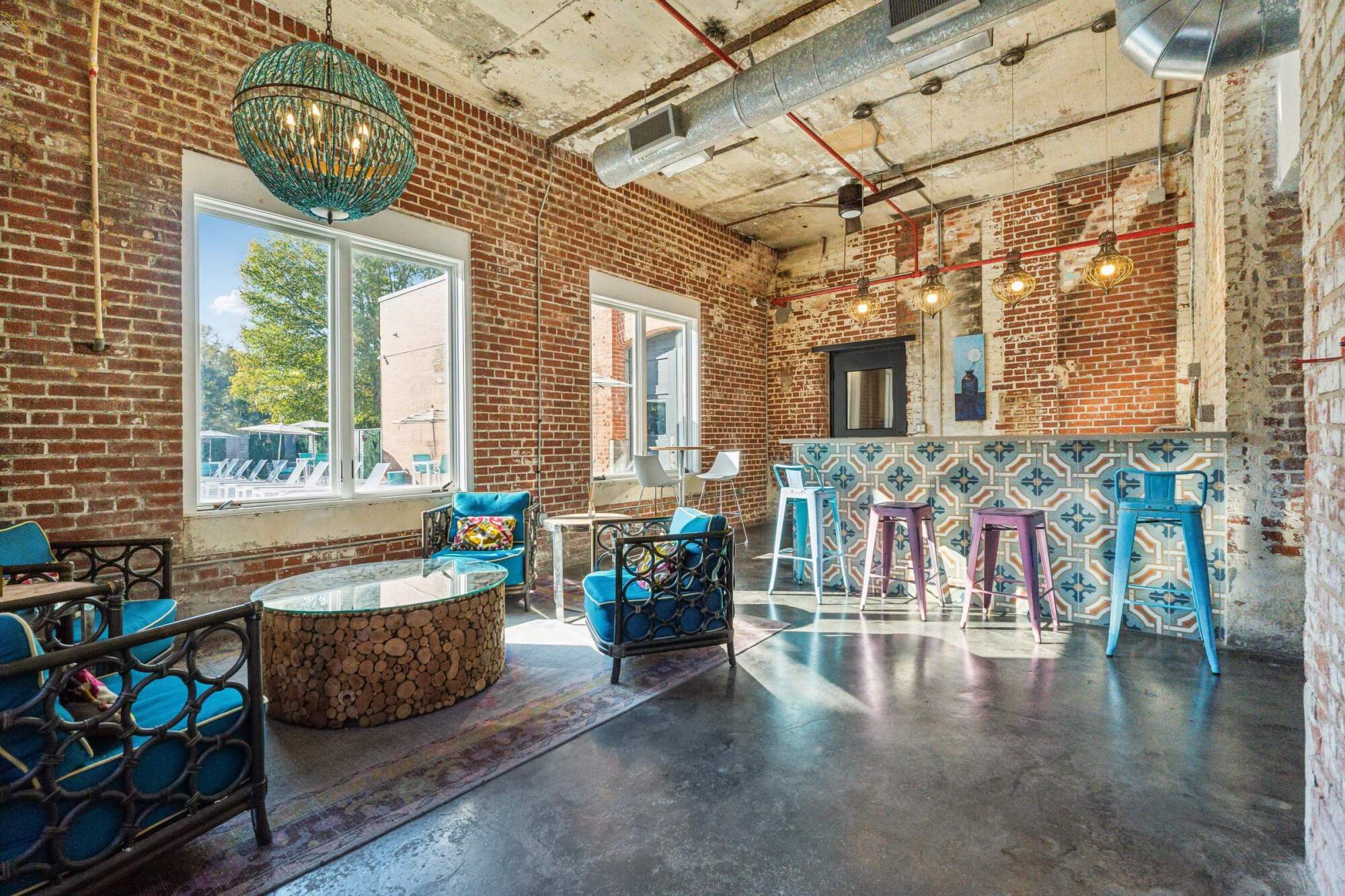 Trendy lounge with brick walls, colorful chairs, a tiled bar, and large windows letting in natural light.